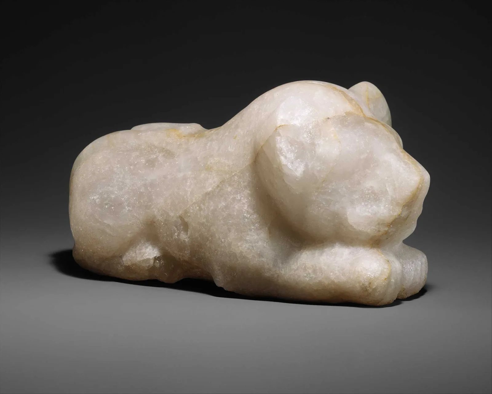 The same figure from the side. The head takes up almost half of the overall size. The boy is lying on his stomach with his head resting on his forelegs.